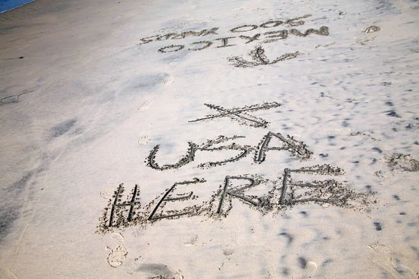 Words in sand. The Words USA HERE X and Mexico 500 yards with an arrow pointing south, written in the sand in San Ysidro California beach close to the US/Mexico border.