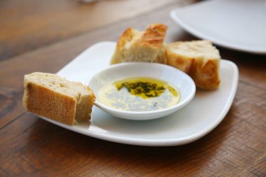 Zeytinyağlı ekmek ve şifalı otlar bir restoranda beyaz bir tabakta. Yemek servis edilmeden önce zeytinyağlı taze ekmek aperatifi..