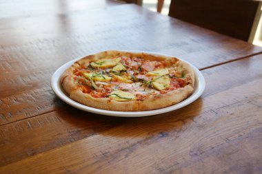 Hawaii pizzası. Öğle yemeği için ahşap bir masada beyaz bir tabakta jambonlu ve ananaslı pizza. Pizza aç insanlar tarafından dünya çapında sevilir. Her yerde pizza.. 