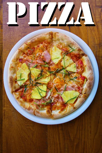 Hawaiian Pizza. A Ham and Pineapple Pizza on a white plate on a wooden table for lunch. Pizza is enjoyed world wide by hungry people. Pizza Pizza Everywhere. Pizza Poster with the word PIZZA.