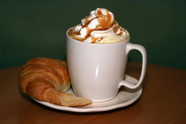 Ceramic cup of coffee on table in coffee shop cafe. Coffee cup latte art in cafe on wooden table. Classic Coffee Cup, Italian Cappuccino. Delicious Morning hot drink. Latte with Croissant. Breakfast drink.