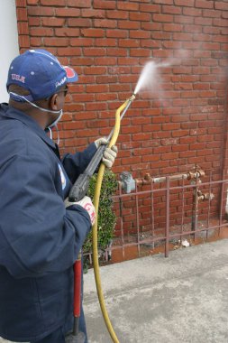 Tanımlanamayan biri, Los Angeles denen Şehir Ormanı 'ndaki duvardan grafiti temizliyor. Basınç yıkama. Tanımlanamayan bir belediye çalışanı Los Angeles şehir merkezindeki kaldırımdan kan ya da ketçap temizliyor..