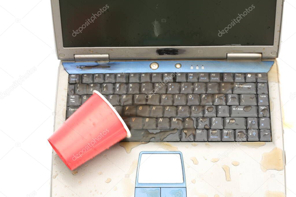 Computer Damage Concept. Coffee Spilled on a Lap Top Computer. Computer Repair and Data Recovery concept. Spill soda from red cup on the computer laptop keyboard. Damage to computer due to spilled liquid. Drink Spilled on a Computer. Computer Repair.