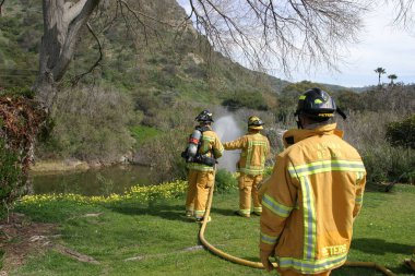 LAGUNA BEACH, CA - 19 Şubat 2009 'da Laguna Beach, Kaliforniya' da yerel itfaiye eğitim alanında yapılan yangın söndürme tatbikatlarında itfaiyeciler su püskürttü. İtfaiyeciler yangın teçhizatı eğitimi alıyor.. 