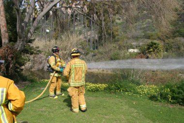 LAGUNA BEACH, CA - 19 Şubat 2009 'da Laguna Beach, Kaliforniya' da yerel itfaiye eğitim alanında yapılan yangın söndürme tatbikatlarında itfaiyeciler su püskürttü. İtfaiyeciler yangın teçhizatı eğitimi alıyor.. 
