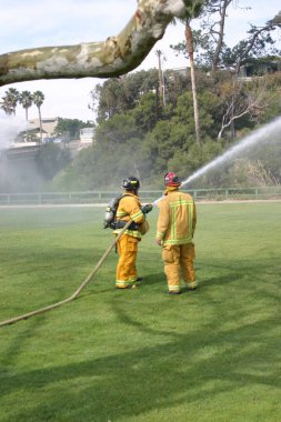LAGUNA BEACH, CA - 19 Şubat 2009 'da Laguna Beach, Kaliforniya' da yerel itfaiye eğitim alanında yapılan yangın söndürme tatbikatlarında itfaiyeciler su püskürttü. İtfaiyeciler yangın teçhizatı eğitimi alıyor.. 