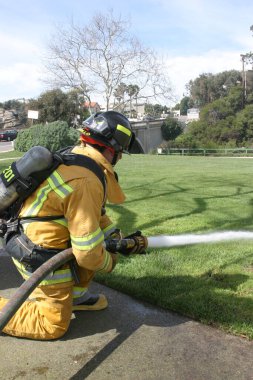 LAGUNA BEACH, CA - 19 Şubat 2009 'da Laguna Beach, Kaliforniya' da yerel itfaiye eğitim alanında yapılan yangın söndürme tatbikatlarında itfaiyeciler su püskürttü. İtfaiyeciler yangın teçhizatı eğitimi alıyor.. 