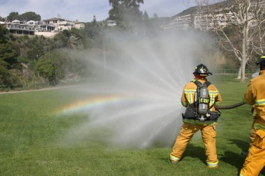 LAGUNA BEACH, CA - 19 Şubat 2009 'da Laguna Beach, Kaliforniya' da yerel itfaiye eğitim alanında yapılan yangın söndürme tatbikatlarında itfaiyeciler su püskürttü. İtfaiyeciler yangın teçhizatı eğitimi alıyor.. 