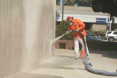 Bir şehir işçisi duvara duvar yazısı yapıştırıyor. Tanımlanamayan kişi, Şehir Ormanı 'nda Los Angeles denen bir duvardan grafiti temizliyor. Buharlı Duvar Temizleme Graffiti Temizleme. 