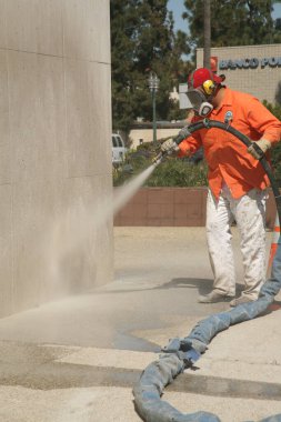 Bir şehir işçisi duvara duvar yazısı yapıştırıyor. Tanımlanamayan kişi, Şehir Ormanı 'nda Los Angeles denen bir duvardan grafiti temizliyor. Buharlı Duvar Temizleme Graffiti Temizleme. 