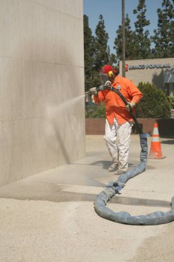 Bir şehir işçisi duvara duvar yazısı yapıştırıyor. Tanımlanamayan kişi, Şehir Ormanı 'nda Los Angeles denen bir duvardan grafiti temizliyor. Buharlı Duvar Temizleme Graffiti Temizleme. 