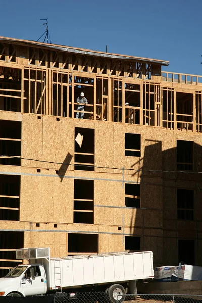 建筑工地 建造中的木框架住宅大楼 在新的物业发展地盘进行建筑 木架结构的施工 参考译文 新住房正在用蓝色天窗建造 — 图库照片