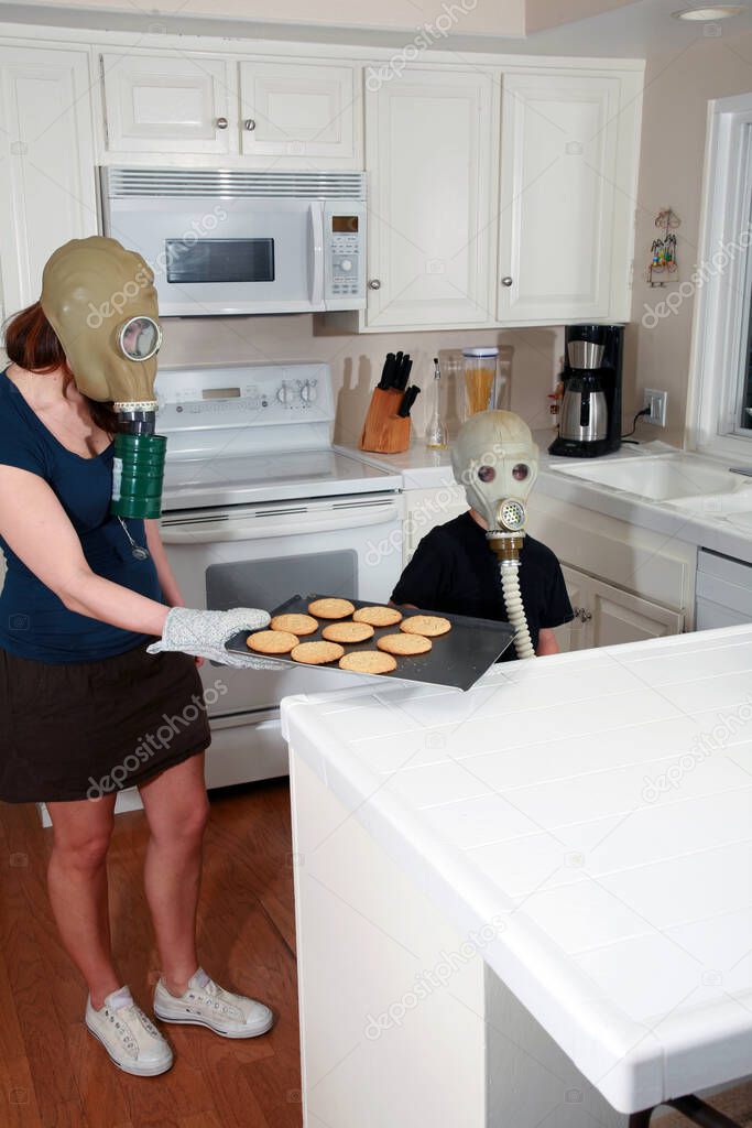 a mother and son enjoy peanut butter cookies in their kitchen while wearing gas masks in a post nuclear winter future. Global Warming Cookie Day. A young family enjoys Cookies while wearing Gas Masks due to Global Warming. After school snack. cookies