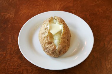 Fırında patates. Tereyağı, ekşi krema, peynirli pastırma ve soğanla dolu fırında patates. Beyazda izole edilmiş. Tabakta yeni pişmiş sade bir patates. Tereyağlı fırında patates. Mükemmel fırında patates..