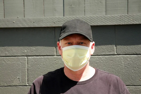 Man wearing a paper mask on his face. A man wears a Medical Face Mask to help avoid contracting Coronavirus aka Covid-19. Covid-19 is an Airborne Illness which has spread world wide. Wear A Mask. Anti Coronavirus Mask. Anti Covid-19 mask. Protection.