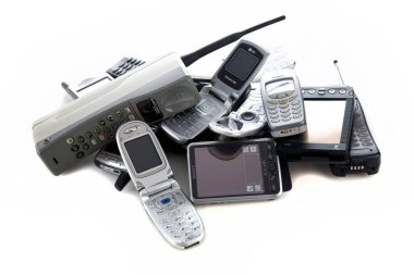 Eski cep telefonları. Eski cep telefonlarının elektronik geri dönüşümü. Bir yığın halinde eski cep telefonları. Beyazda izole edilmiş. Mesaj için yer var. Kullanılmış eski cep telefonları. Eski masabaşı telefonları, kablosuz telefonlar, cep telefonları ve akıllı telefonlar beyaz arka planda bir yığın halinde yatıyor..  
