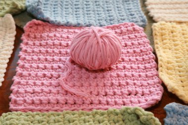 Tığ işi. Pamuk ipliklerle örgü örmek. Pamuk ipliğiyle tığ işi. Masada tığ işi desenleri var. Tığ işi, yakın plan. Tığ işi kalın iplik hobisi. Örgü kancasıyla farklı renklerde iplikler. Örgü, tığ işi malzemeleri. İplik.