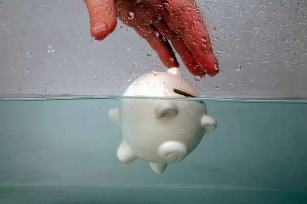 Drowning in Debt. a piggy bank sinks in dark murky water. drowning in debt. keeping your head above water. financial concepts. help at financial crisis. Financial Aid and rescue from debt problems. drowning piggy bank sinking in blue water.