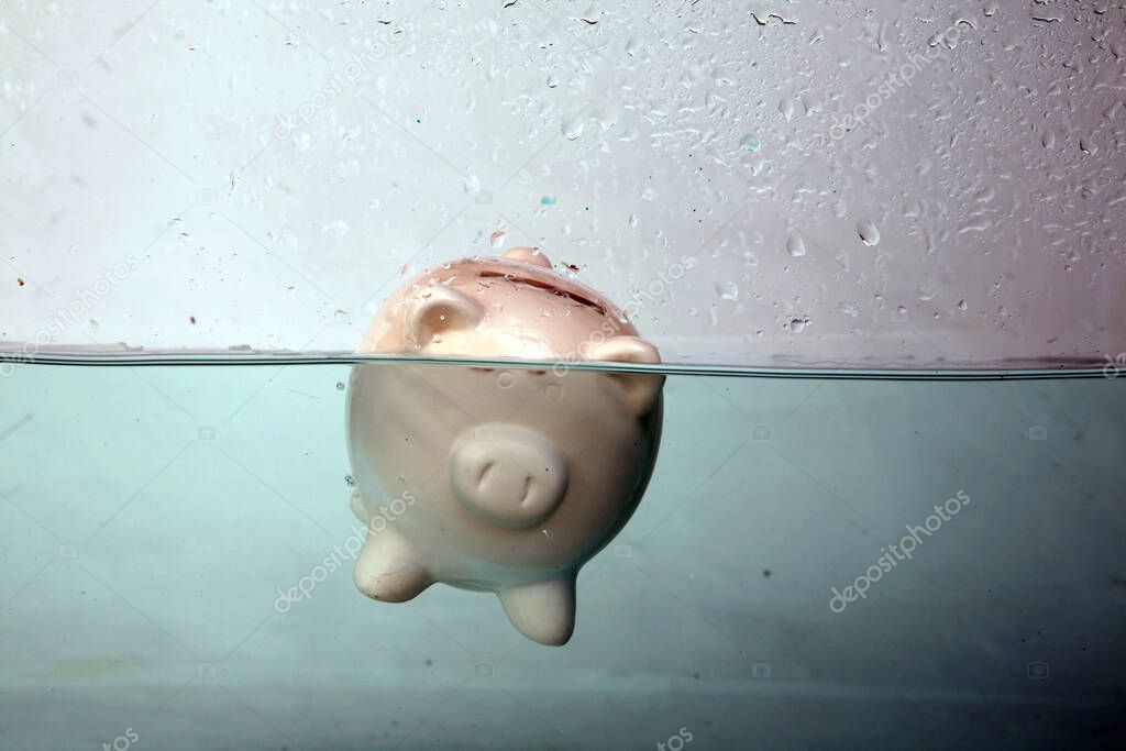 Drowning in Debt. a piggy bank sinks in dark murky water. drowning in debt. keeping your head above water. financial concepts. help at financial crisis. Financial Aid and rescue from debt problems. drowning piggy bank sinking in blue water. 