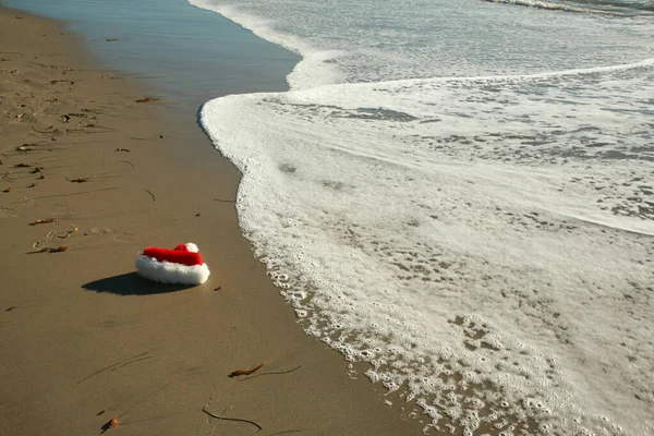 Jultomten Hatt Stranden Jultomte Hatt Ligger Stranden Med Havsvågorna Försiktigt — Stockfoto