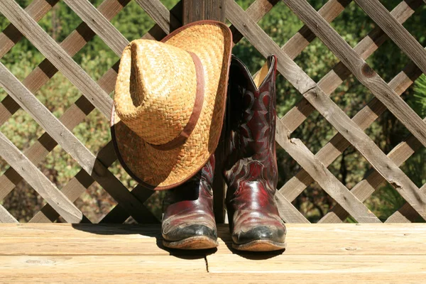 Cowboy Boots. Western Wear. Cowboy Boots, Cowboy Hat and Six Shooter Pistol. A pair of red leather western boots with a golden straw hat. Rustic western image of cowboy boots, cowboy hat, and Gun. decorative cowboy boots. Cowboy boots and hat.