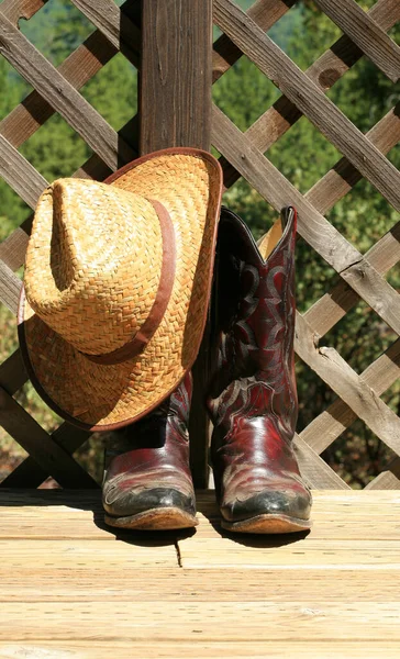 Cowboy Boots. Western Wear. Cowboy Boots, Cowboy Hat and Six Shooter Pistol. A pair of red leather western boots with a golden straw hat. Rustic western image of cowboy boots, cowboy hat, and Gun. decorative cowboy boots. Cowboy boots and hat.