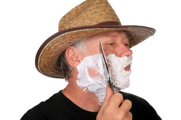牛仔刮胡子一个牛仔用他的刀刮胡子用鲍伊刀刮粗糙而坚硬的牛仔脸 一个真正的牛仔用一把大刀刮胡子 用白色隔开 有地方放你的课本 — 图库照片