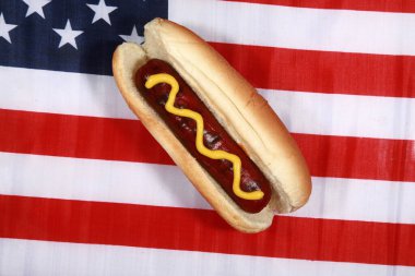 Sosisli sandviç. 4 Temmuz Hot Dog. Barbekü Partisi Yemeği. Amerikan bayrağı taşıyan vatansever bir sosisli sandviç. 4 Temmuz 'da Amerika Birleşik Devletleri' nde Bağımsızlık Günü 'nü kutluyoruz. Bağımsızlık Günü sosislisi. Sosisliler Tatiller ve Partiler için Mükemmel Yemekler.