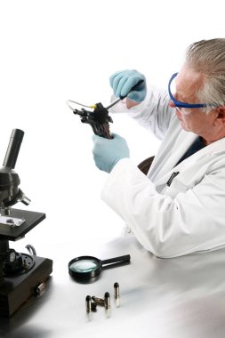 Adli Analiz. Polis dedektifi olay yerinden toplanan delilleri belgeliyor. Adli tıp müfettişi. Adli tıp dedektifi bir silahtan ve bir suçta kullanılan mermilerden kanıt topluyor. Hematolojik test kiti. Suç laboratuarı. Suç mahalli.