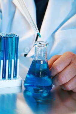 Kimya. Temiz cam matara ve mavi solüsyonlu deney şişesi. Bilim araştırma laboratuvarı. Bilim adamı Coronavirus için bir tedavi üzerinde çalışıyor. Covid-19 araştırma laboratuarı salgın için bir tedavi üzerinde çalışıyor. Tıbbi Araştırma Laboratuarı. Covid-19 Tedavi Araştırması.