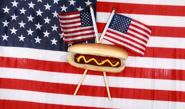 Sosisli sandviç. 4 Temmuz Hot Dog. Barbekü Partisi Yemeği. Amerikan bayrağı taşıyan vatansever bir sosisli sandviç. 4 Temmuz 'da Amerika Birleşik Devletleri' nde Bağımsızlık Günü 'nü kutluyoruz. Bağımsızlık Günü sosislisi. Sosisliler Tatiller ve Partiler için Mükemmel Yemekler.