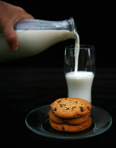 ミルクとクッキー ミルクとチョコレートチップクッキー 1つの大きなチョコレートチップクッキーと新鮮な冷たいミルクのレトロなボトル ミルクボトルとクッキー 昔ながらの料理やお菓子 黒ベルベットに隔離された牛乳とクッキーのガラス — ストック写真