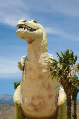 Dinozor. T-Rex. Tyrannosaurus heykeli Palm Springs, California yolunda bir yol kenarı çekiciliği olarak kullanılıyor. 1950 'lerden kalma dinozorların yol kenarı cazibesi hala ziyaretçileri cezbediyor ve ziyaret etmeye cesaret edenleri dehşete düşürüyor.. 