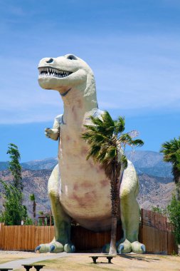 Dinozor. T-Rex. Tyrannosaurus heykeli Palm Springs, California yolunda bir yol kenarı çekiciliği olarak kullanılıyor. 1950 'lerden kalma dinozorların yol kenarı cazibesi hala ziyaretçileri cezbediyor ve ziyaret etmeye cesaret edenleri dehşete düşürüyor.. 