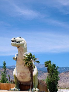 Dinozor. T-Rex. Tyrannosaurus heykeli Palm Springs, California yolunda bir yol kenarı çekiciliği olarak kullanılıyor. 1950 'lerden kalma dinozorların yol kenarı cazibesi hala ziyaretçileri cezbediyor ve ziyaret etmeye cesaret edenleri dehşete düşürüyor.. 