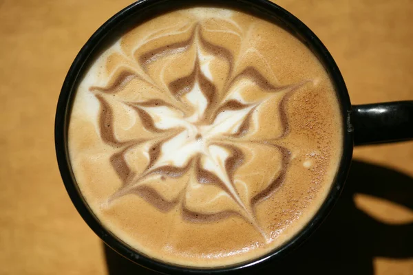 Latte. Latte Art. Latte art on hot latte coffee . Milk foam in a leaf pattern on top of latte art from a professional barista artist. Coffee Latte Art. The coffee arts. Hot coffee in a cup on a table. Hot chocolate latte art on table.