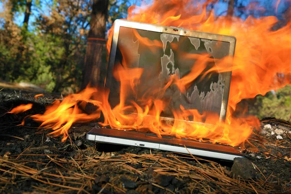 Computer Damage. Computer Fire. A laptop computer engulfed in flames of hot fire. Smoke and Fire burn and melt a computer. Computer damage. data destruction. molten computer keyboard is burning and covered in fire and smoke. computer damage.