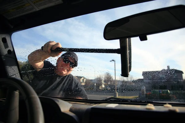 Car Window Washing. Washing and cleaning the front window of a car. self service car wash. car window cleaning. male cleaning car windshield with brush and soapy water. cleaning automobile. automobile windows. window cleaning. car wash. gas station.