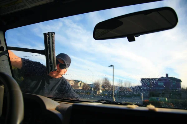 Car Window Washing. Washing and cleaning the front window of a car. self service car wash. car window cleaning. male cleaning car windshield with brush and soapy water. cleaning automobile. automobile windows. window cleaning. car wash. gas station.