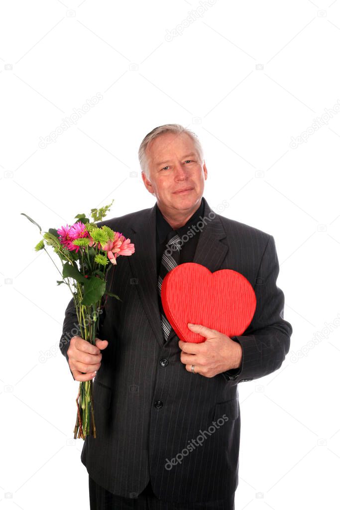 Valentines Day. A man in a nice suit has fresh flowers and a hear shaped box of chocolates for a Valentine's Day Gift. Isolated on white. Room for text. Clipping Path. Hearts represent love world wide. Valentine's Day is when people give gifts. 