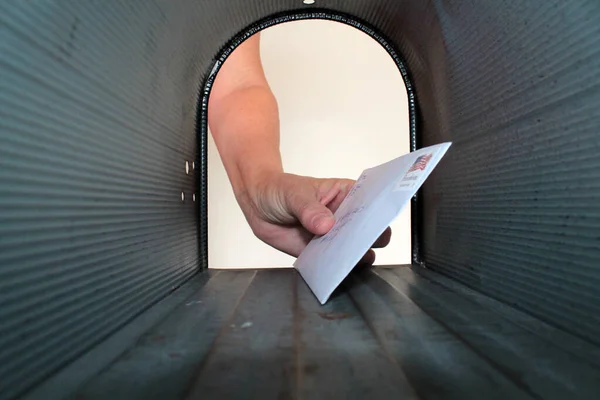 Mail. Man receiving letters and bills in mailbox in front of house. mail delivery. Mail box over-stuffed with bills. junk mail. spam. unwanted correspondence. mailing a letter. receiving a letter. letter in the mail box. love letter. ransom note.