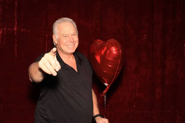 Photo Booth. Man in a Photo Booth. Photobooth. Customer enjoys a photo booth. A man smiles as he has his photo taken in a Photo Booth. Man in a Photo Booth. A man smiles and poses in a Photo Booth with red velvet. Photo Booths are fun for all guest.