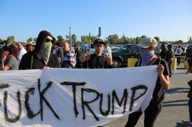 Costa Mesa, CA - 28 Nisan 2016: Kosta Mesa CA 'da düzenlenen mitingde protestocular cumhuriyetçi başkan adayı Donald Trump' ın destekçilerini engellemeye, slogan atmaya ve slogan atmaya çalıştılar. Başkan Donald Trump. Tanrı Amerika 'yı korusun.. 