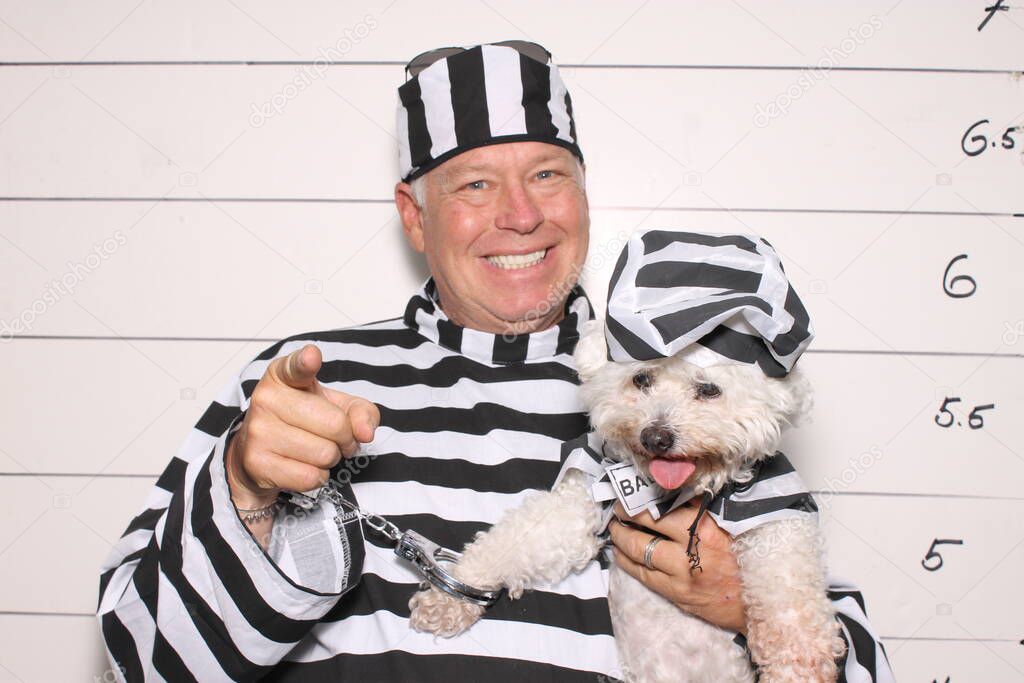 Photo Booth. Mug Shot Photo Booth. A Criminal is arrested and has his photo taken. Booking Photo. Police mug shots of a male criminal and his dog, standing in front of a Mug Shot Wall. Line Up. Under arrest. mug shot of middle aged man and his dog.