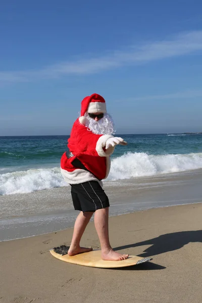 圣诞节 圣诞老人 圣诞老人冲浪 冲浪圣诞老人 冲浪圣诞老人 圣诞老人在他的冲浪板上冲浪 而在美丽的海滩与蓝色的海洋 关注圣诞老人的面部圣诞假期 圣诞老人去冲浪 海滩上的圣诞老人 — 图库照片