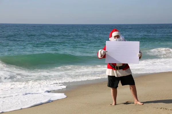 圣诞节 圣诞老人 带着白纸标志的圣诞老人在海滩 文字空间 圣诞老人拿着白纸标志 圣诞老人与空白标志隔离 给你的文字或形象留有空间 圣诞快乐 节日快乐 献上节日的问候 — 图库照片
