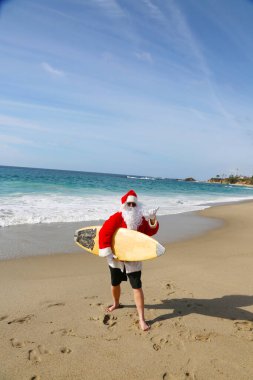 Noel Baba 'da sörf. Noel zamanı. Noel tatili. Noel Baba 'da sörf. Sörf tahtası. Sıkı tutun. Noel Baba tatildeyken dalgaları kontrol eder. Noel arifesinde Noel Sörfü. Noel Baba ve sörf tahtası. Noel Baba sörf tahtasında sörf yapıyor. Sörfler yukarı. 
