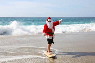 Noel Baba 'da sörf. Noel zamanı. Noel tatili. Noel Baba 'da sörf. Sörf tahtası. Sıkı tutun. Noel Baba tatildeyken dalgalarda sörf yapar. Noel arifesinden önce Noel Sörfleri. Noel Baba ve sörf tahtası. Noel Baba sörf tahtasında sörf yapıyor. Sörfler yukarı.