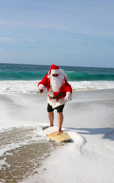 Surfing Santa Claus. Christmas. Christmas Vacation. Surfing Santa. Surf Board. Hang Ten. Santa Claus Rides the waves while on Vacation. Santa Surfs before Christmas Eve. Santa Claus and surf board. Santa Claus Surfs on his Surf Board. Surfs up.