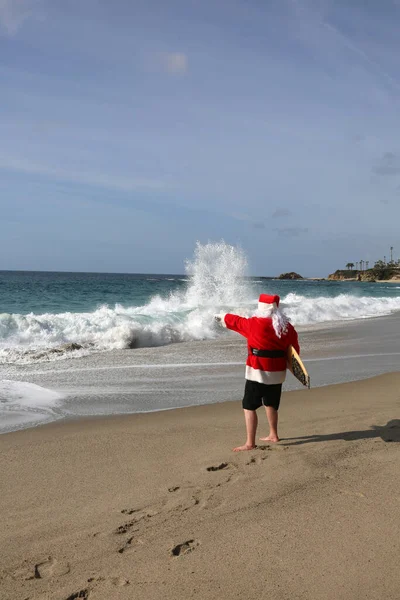 Surfing Santa Claus. Christmas. Christmas Vacation. Surfing Santa. Surf Board. Hang Ten. Santa Claus Checks out the waves while on Vacation. Santa Surfs on Christmas Eve. Santa Claus and surf board. Santa Claus Surfs on his Surf Board. Surfs up.